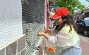Voluntarios pintan cortinas de locales comerciales en el centro de Villa Alemana.