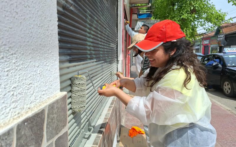 Voluntarios pintan cortinas de locales comerciales en el centro de Villa Alemana.